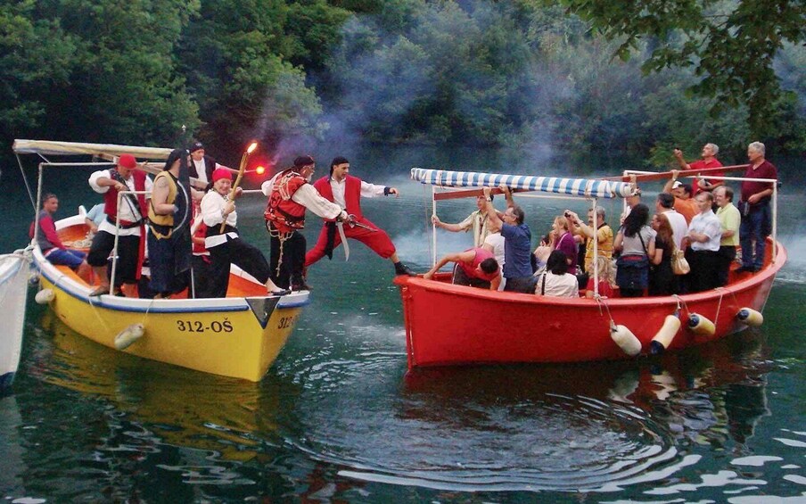 Two boats with people on them, one yellow and one red, on a body of water with trees in the background. 3
