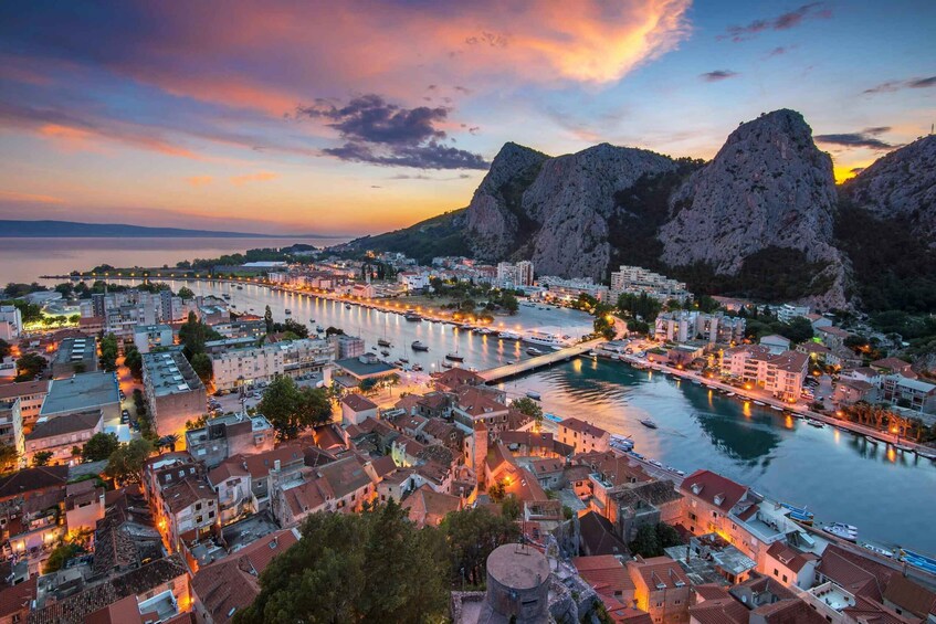 A coastal cityscape at dusk with a marina, buildings, and prominent rocky cliffs. 4