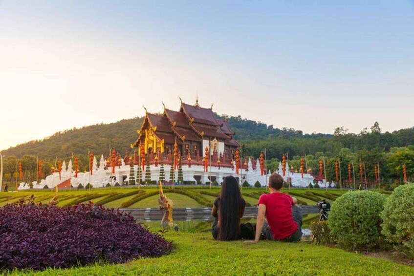A traditional temple with ornate architecture, a well-maintained garden, and a hilly backdrop. 1
