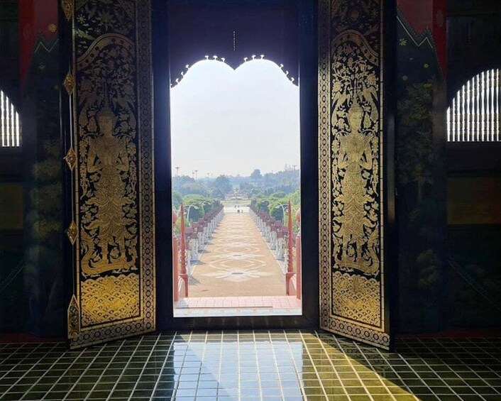 An ornate doorway with intricate designs and a view of a pathway leading to a distant landscape. 2