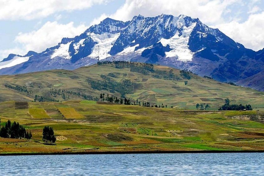 A mountainous landscape with a lake in the foreground and snow-capped peaks in the background. 3
