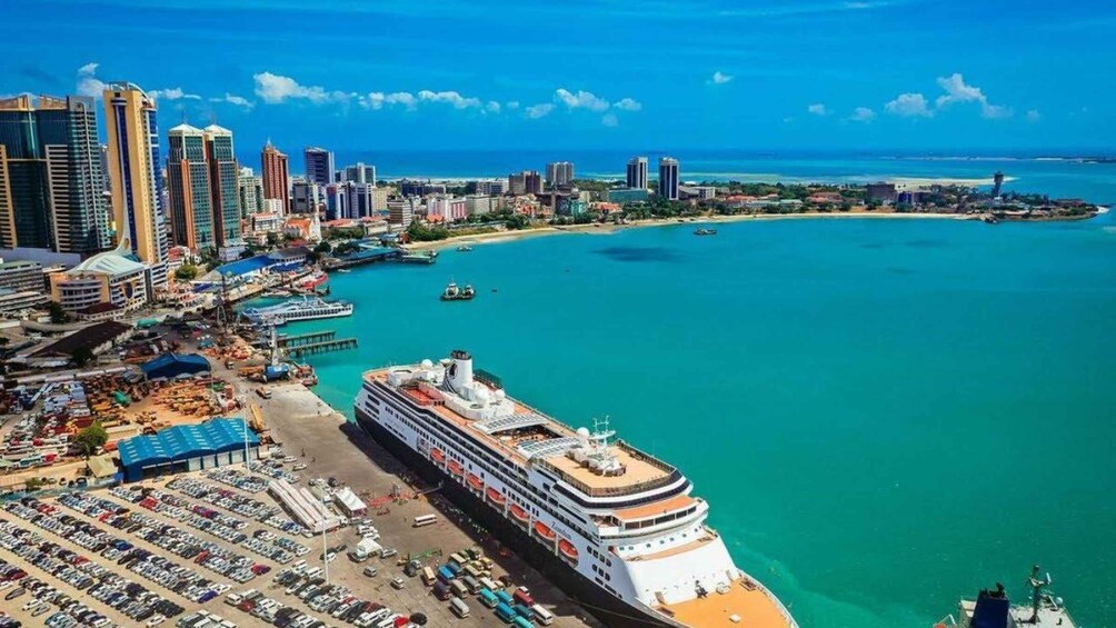 A cruise ship docked at a port with a cityscape in the background. 2