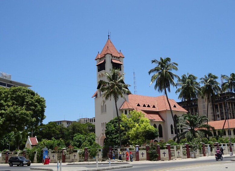 A church with a tall bell tower and palm trees. 1
