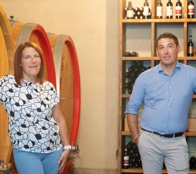 Two people in a wine cellar with wooden racks and bottles. 2