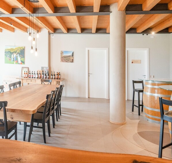 A spacious room with a long wooden table, chairs, and a wine rack with bottles. 1