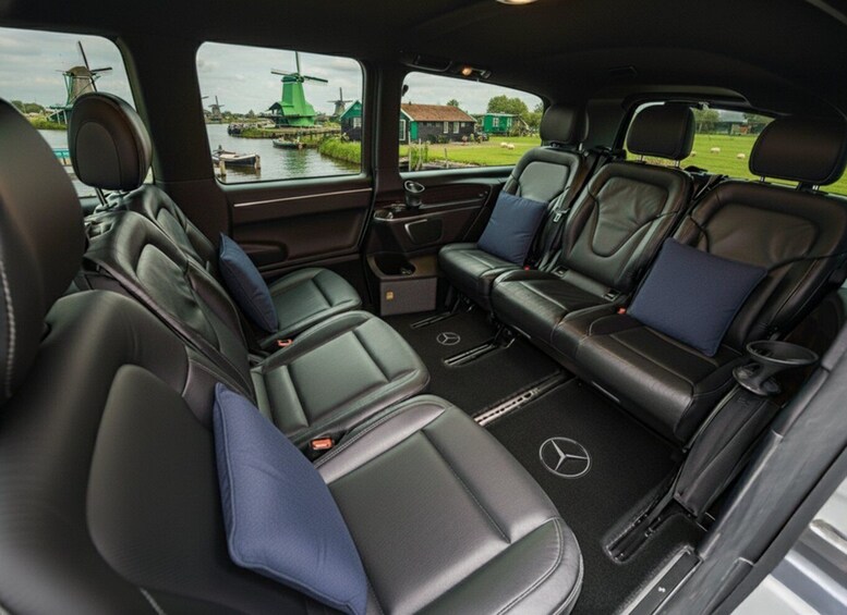 A car interior with black leather seats, a central console, and a view of windmills and water through the windows. 4