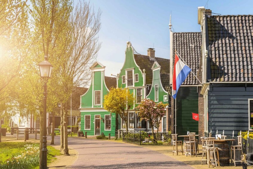 A green traditional Dutch house with a flag, a cobblestone street, and a bench. 2