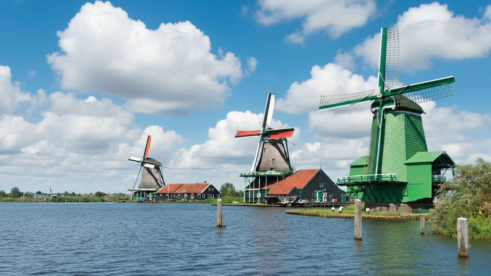 Three windmills by a calm lake with a clear sky. 3