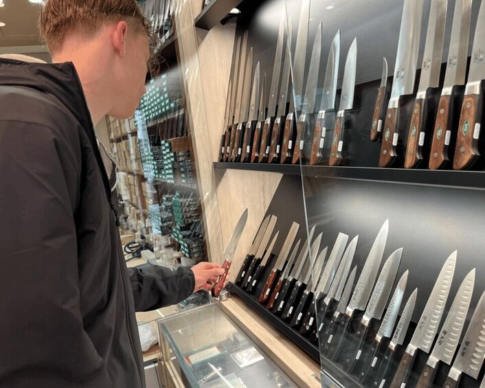 A person examining knives in a store. 4