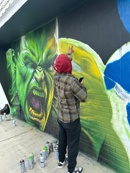 Una persona dipinge un murale su un muro di mattoni. 2