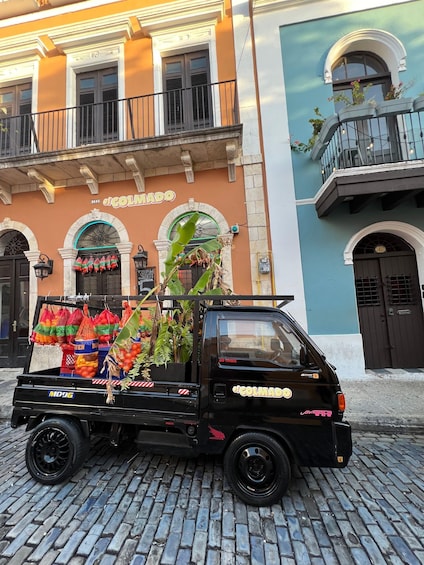 A black Honda truck parked on a cobblestone street in front of a building with a sign reading 'El Colmado.' 5