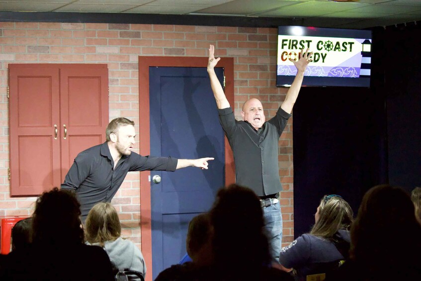 A comedy show with a stage, audience, and a sign reading 'FIRST COAST COMEDY'. 2