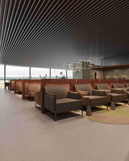 A modern lounge with sofas and tables, a patterned ceiling, and a view of the city. 1