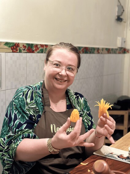 A person holding two pieces of food, possibly food items, in a kitchen setting. 2