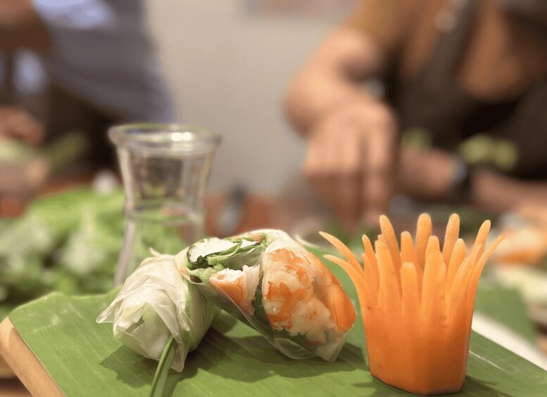 A food presentation with a spring roll and carrot garnish on a green leaf. 3