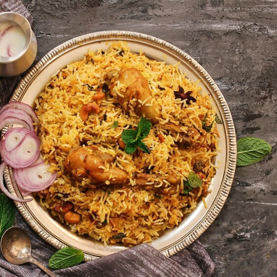 A plate of biryani with chicken, garnished with mint leaves. 1