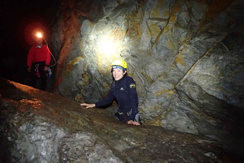 A person in a cave with a headlamp, wearing a helmet and harness. 1