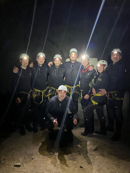 A group of people in helmets and harnesses, posing for a photo in a dimly lit setting. 3