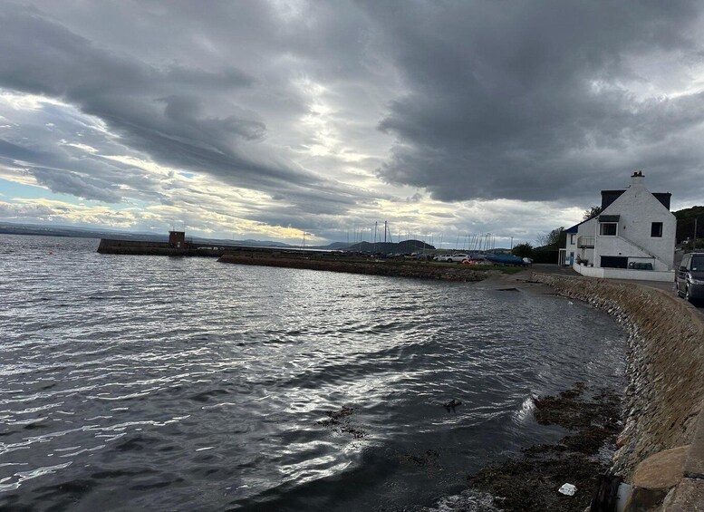 A coastal scene with a white building, a breakwater, and boats in the background. 2