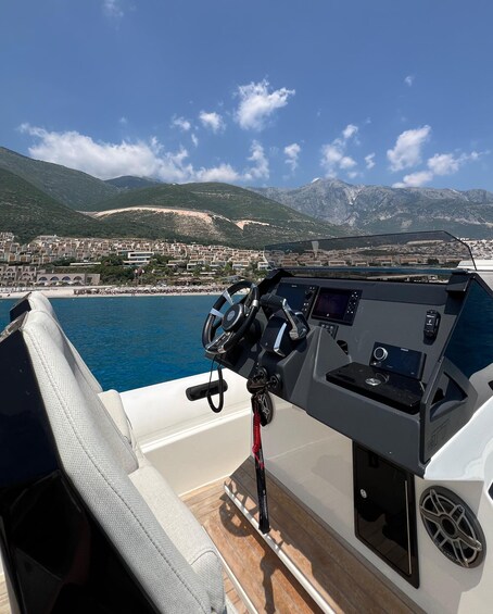 A boat's control station with a view of a coastal town and mountains in the background. 5
