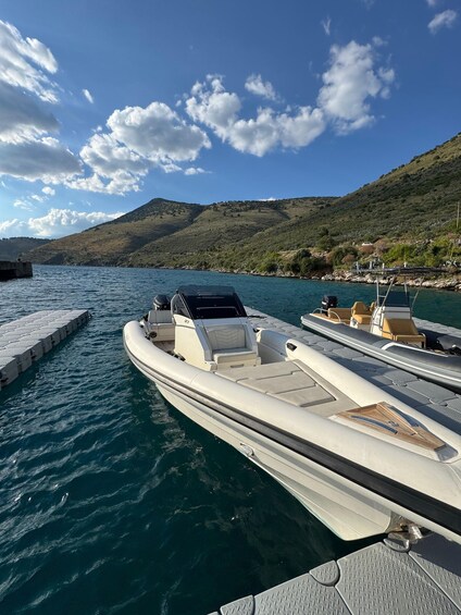 A row of motorboats docked at a pier with a mountainous backdrop. 1