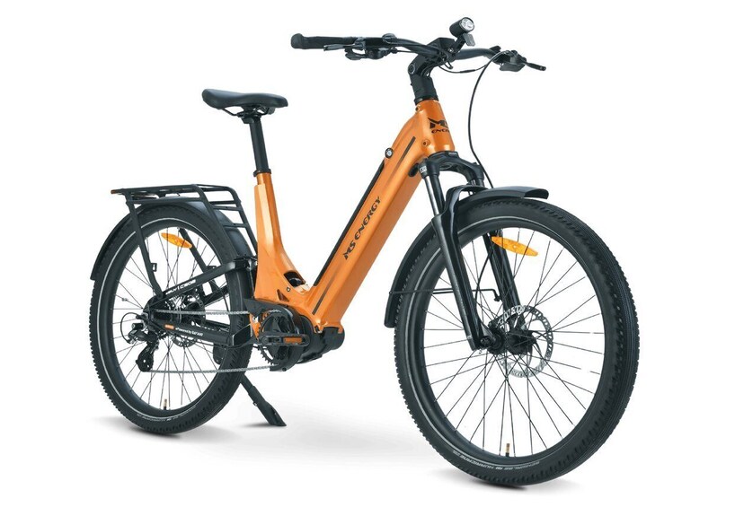 A stationary electric bicycle with a black and orange frame, a rear rack, and thick tires. 5