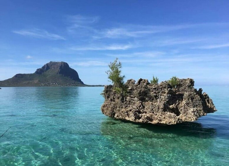A clear blue sea with a rocky island and a mountain in the distance. 3