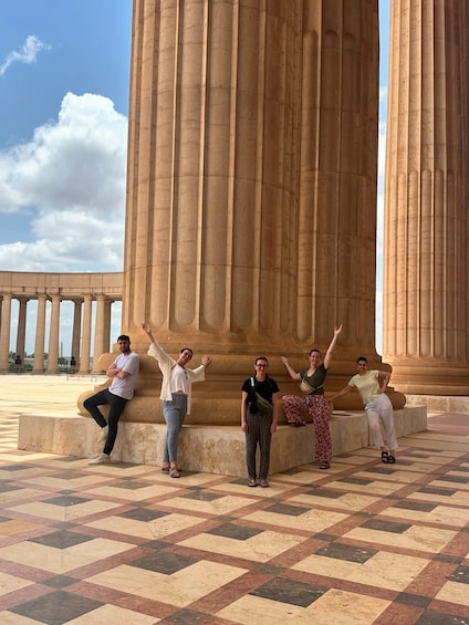 A group of people posing in front of a large classical column structure. 4