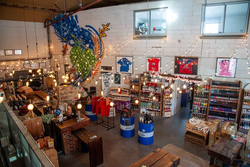 A cozy bar with wooden furniture, string lights, and various bottles and clothing items on display. 4