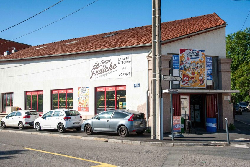 A building with a sign for 'La Grosse Fraiche' and parked cars in front. 3