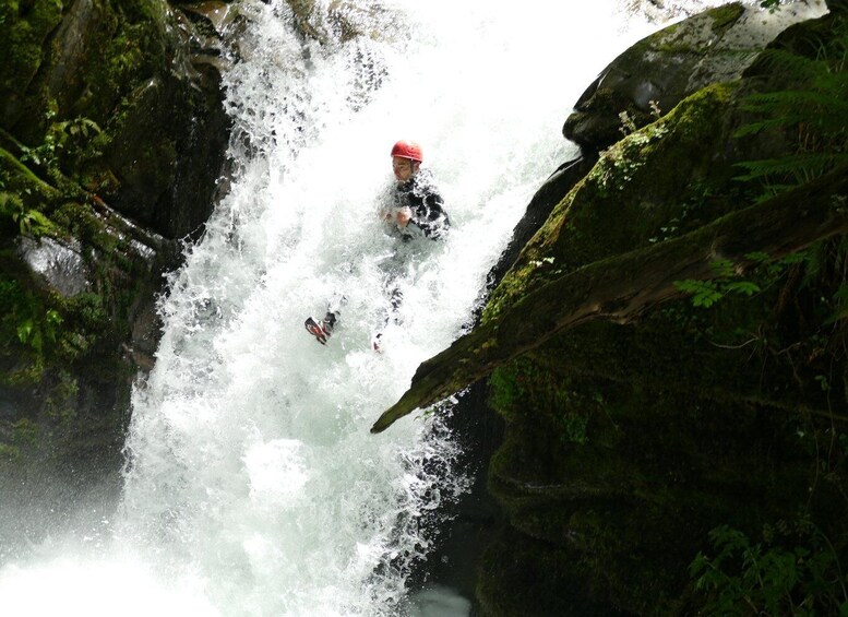 A kayaker navigating a turbulent waterfall surrounded by lush greenery. 4
