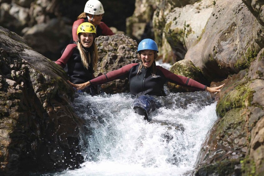 A person in a wetsuit and helmet navigating a rocky watercourse. 5