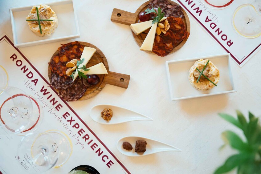 A table with various food items and a menu titled 'RONDA WINE EXPERIENCE.' 3