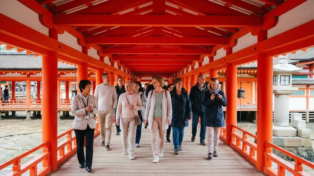 A group of people walking on a wooden bridge with red pillars. 3