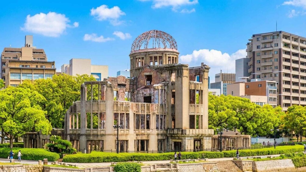 A historic building with a dome, surrounded by modern buildings and lush green trees. 1