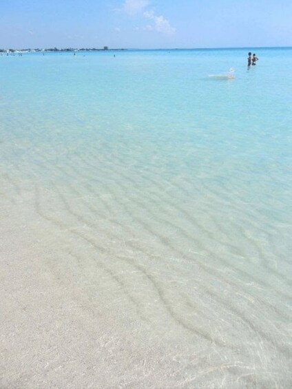 A clear beach with gentle waves and a distant shoreline. 2