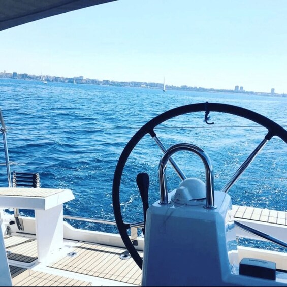 A boat's steering wheel and deck with a view of the water and distant city skyline. 5