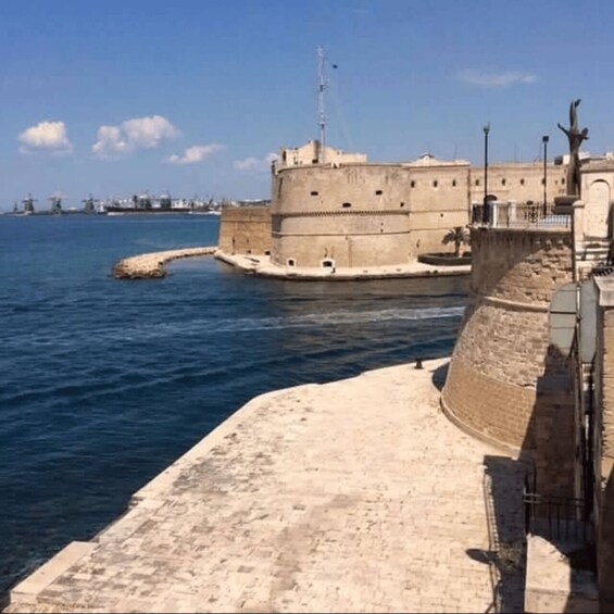 A coastal fortification with a large tower, a sandy breakwater, and calm sea. 3