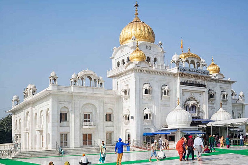 A white building with golden domes and a green carpeted area in front. 5
