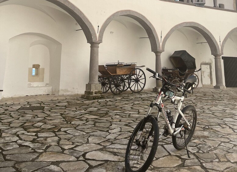 A cobblestone courtyard with a bicycle, a wooden cart, and a grill. 5