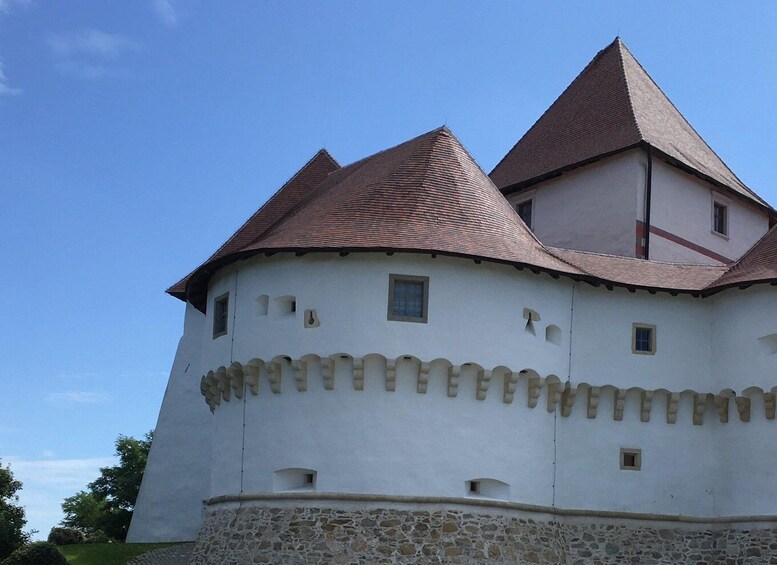 A white castle with a stone base and red-tiled roofs. 2