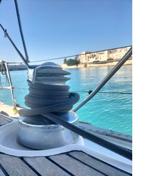 A coiled rope on a boat's winch, calm water, and a distant shoreline with buildings. 5