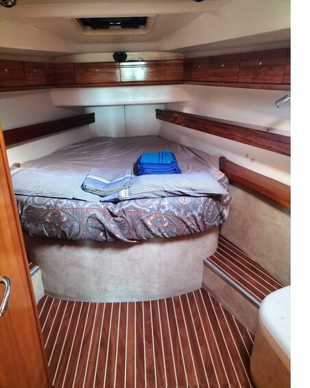 A compact, well-organized cabin with a bed, neatly folded clothes, and a small bathroom area. 4