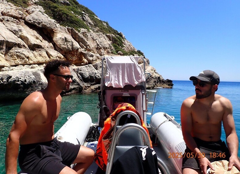 Two men on a boat near rocky cliffs with clear blue water. 5