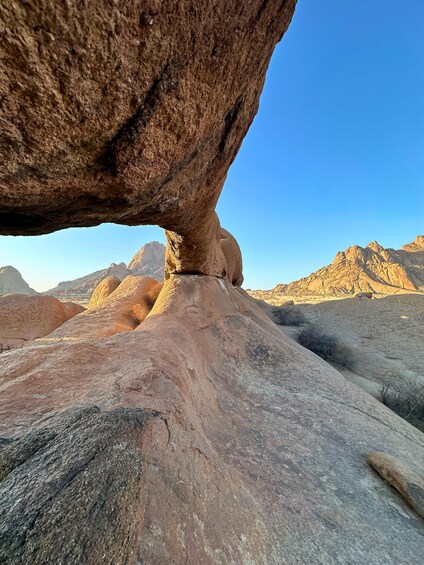 A rock formation with a natural archway and a desert landscape in the background. 5