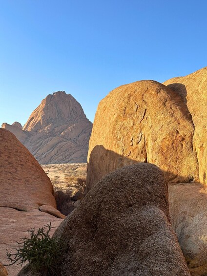 A desert landscape with large rock formations and a clear blue sky. 3