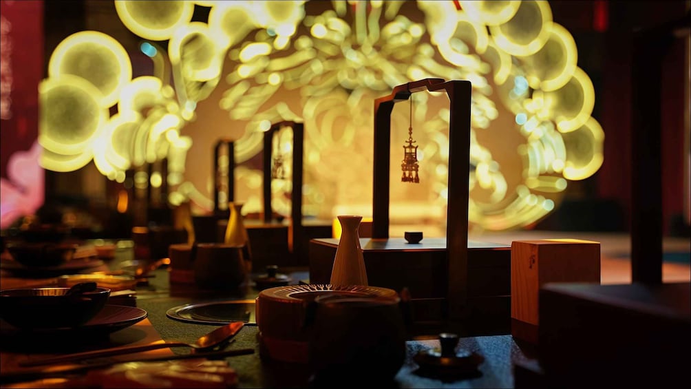 A dimly lit room with a series of hanging lanterns and a central table with a vase and a candle. 3