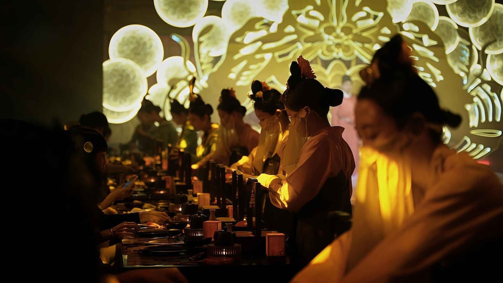 A dimly lit restaurant with patrons seated at tables, illuminated by soft ambient lighting and decorative light patterns on the ceiling. 4