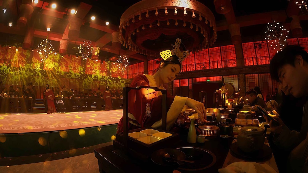 A traditional Chinese restaurant interior with a stage, tables, and a decorative ceiling. 2