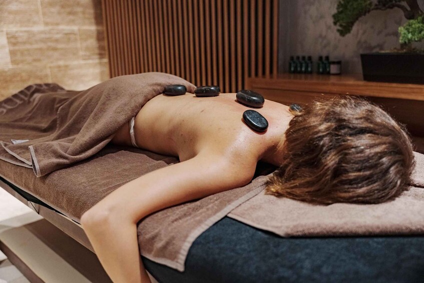 A person receiving a stone massage on a massage table. 4